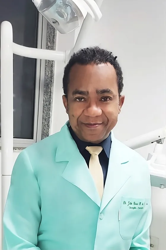 Dr. Júlio César Xavier Oliveira sorrindo em seu consultório odontológico